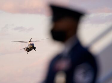Soldier stands as a helicopter lands in the background.