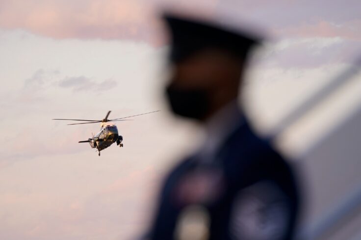 Soldier stands as a helicopter lands in the background.