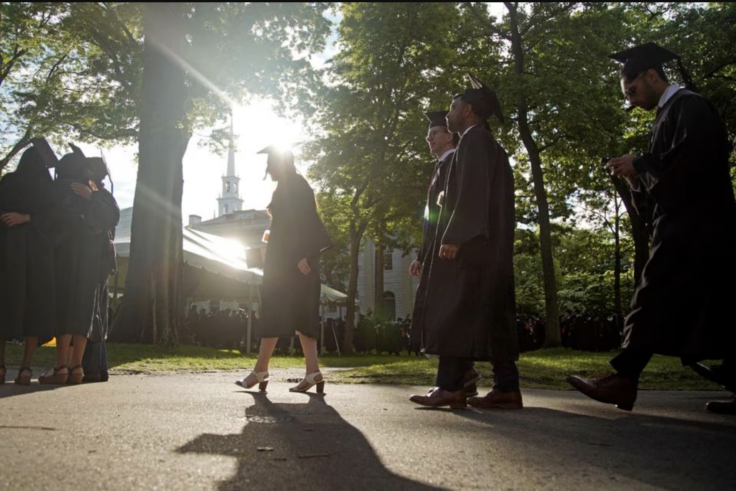Students in graduation outfits walking in Harvard Yard