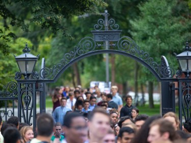 A crowd walking through a Harvard gate