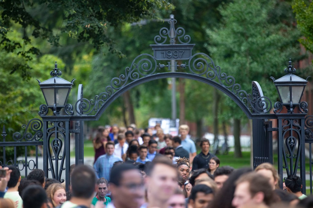 A crowd walking through a Harvard gate