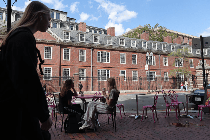 women sitting at a cafe in Harvard Square while another woman walks by.