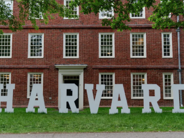 Larger white letters stand against Mass Hall. They spell out "Harvard".