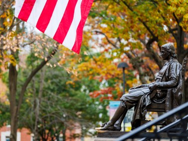 The John Harvard Statue with an American flag