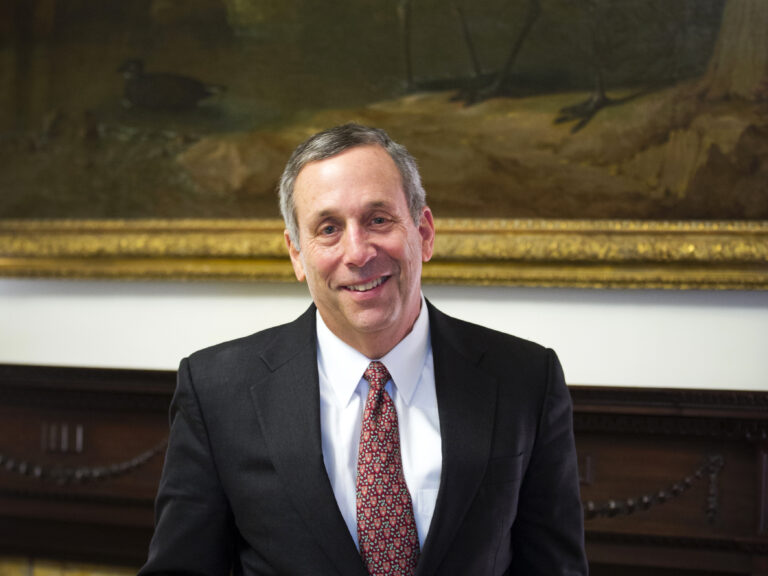 Larry Bacow in front of a painting of a crain