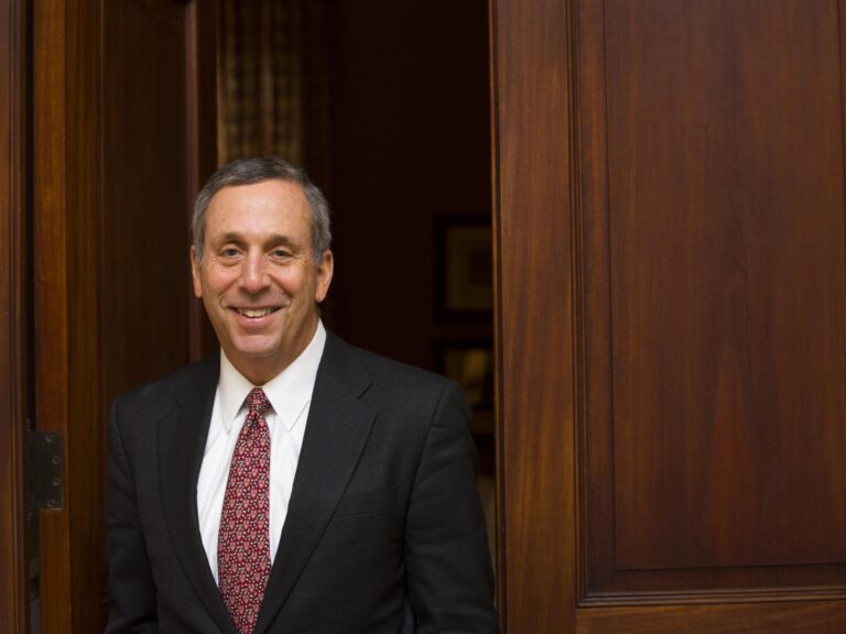 Larry Bacow walking out of a door.