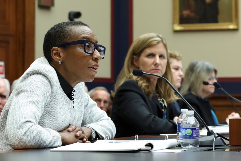 Claudine Gay speaks into a microphone seated behind a desk.