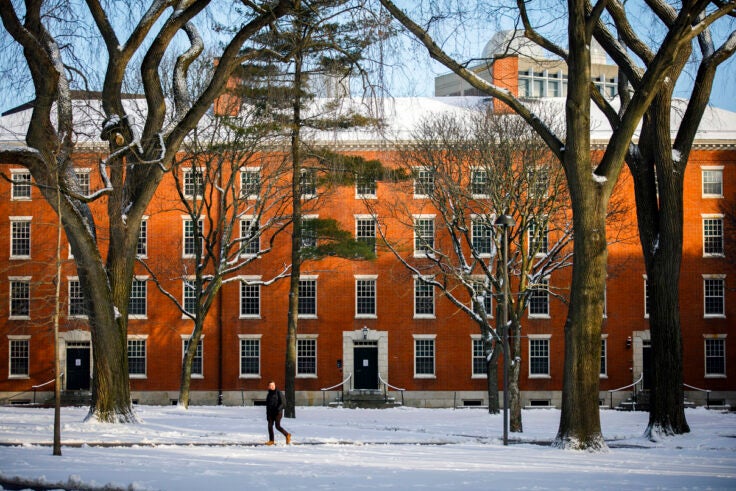 person walking across a snow-covered Harvard Yard