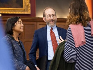 President Garber speaking with two women at Cambridge College.