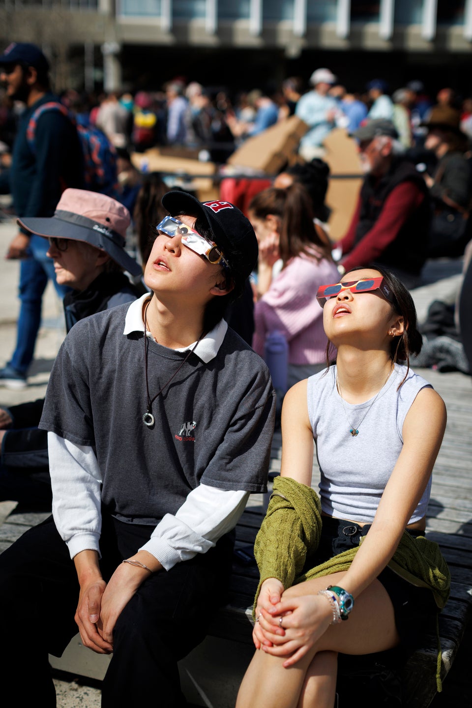 Two people wearing solar glasses look skyward in awe.