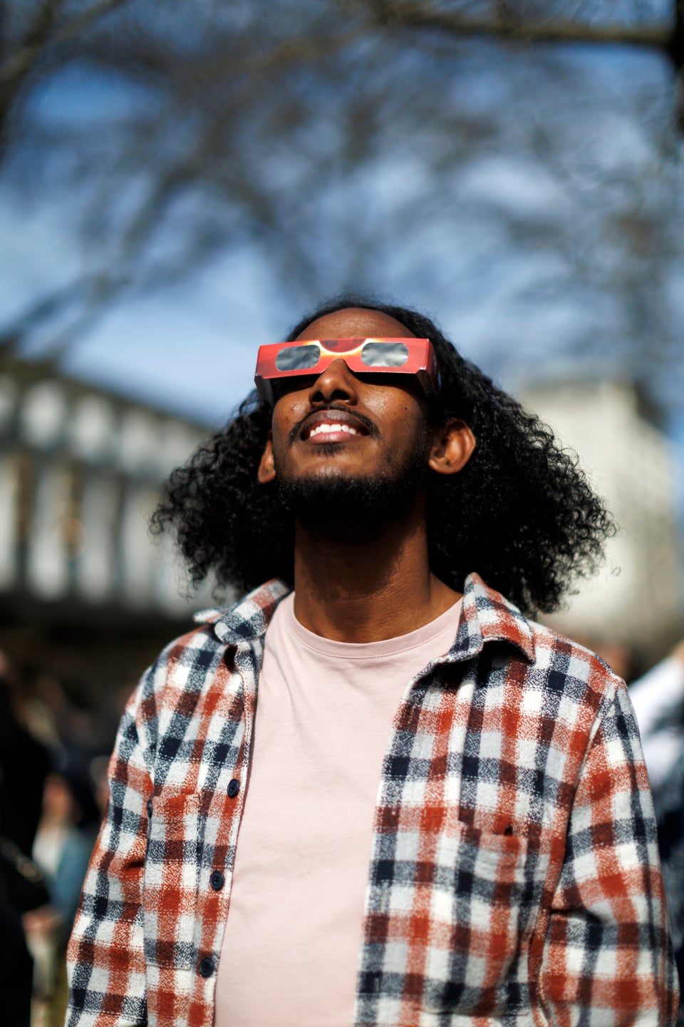 A man wearing solar glasses looks skyward.