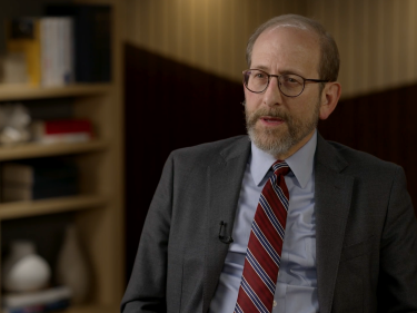 Alan Garber speaking to an interviewer in a suit and tie.