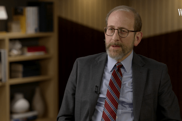 Alan Garber speaking to an interviewer in a suit and tie.