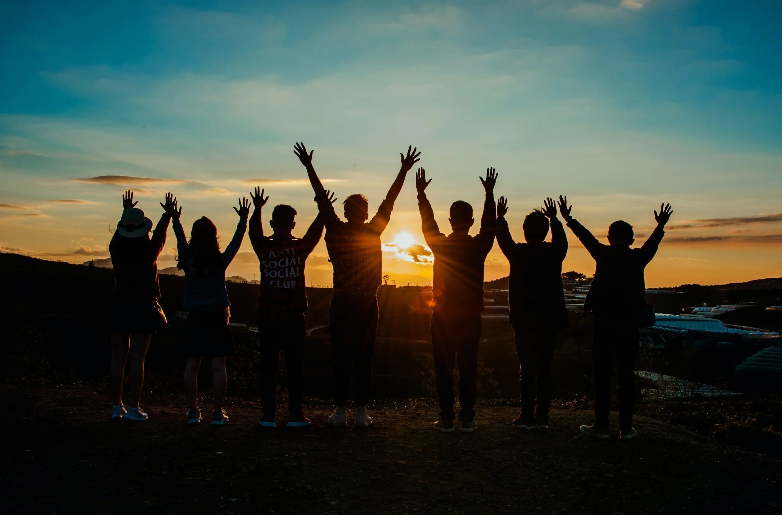 people celebrating in front of a setting sun