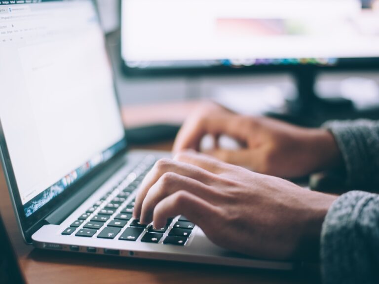 Person's hands typing on a laptop