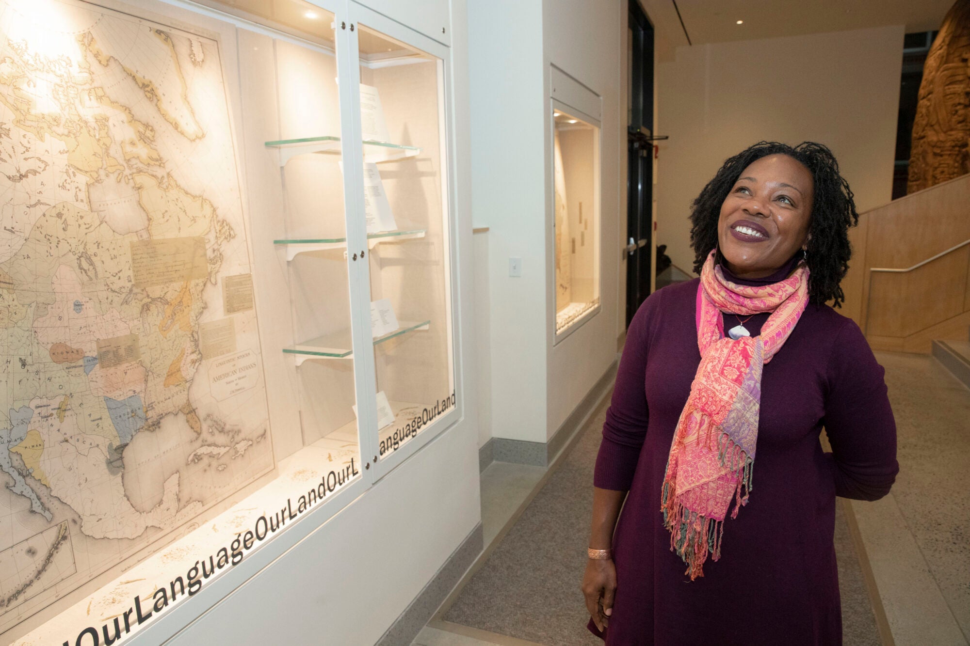 A woman stands by an art exhibit smiling.