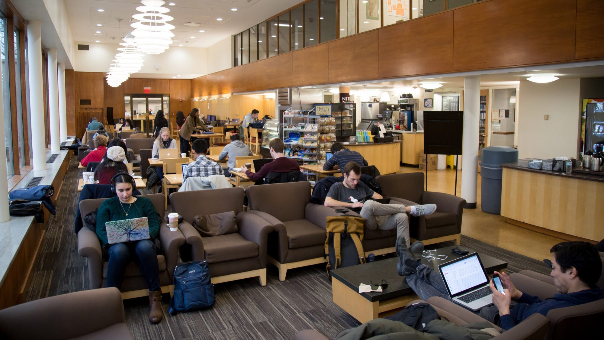 A room filled with students sitting on couches studying.