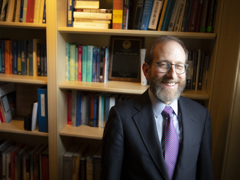 Alan Garber smiling at camera in front of a bookshelf