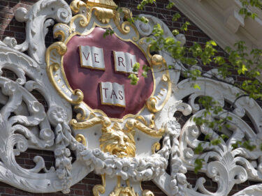 Veritas on a Harvard building with flowers