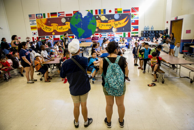 Two students stand in front of a classroom