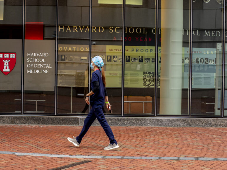 Someone in scrubs walking on the dental school campus