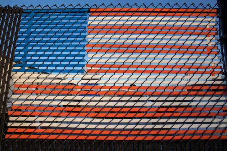 An American flag made with plastic strips on a fence