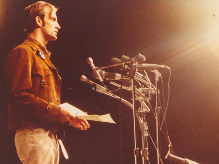 An older photo of Denis Hayes speaking on a stage