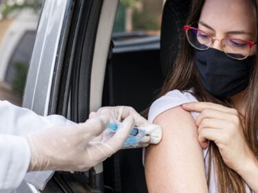 woman in car having a vaccine administered.