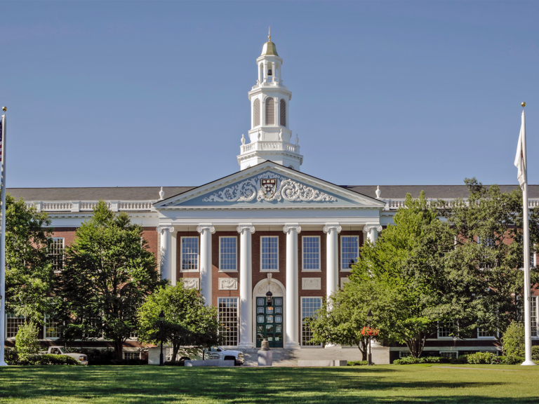 The facade of Baker Library against a bright blue sky.