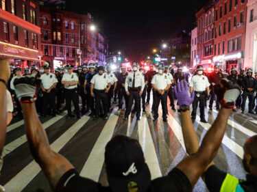 a line of police approaching people with their hands up