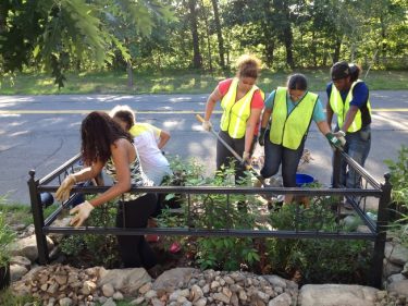 People cleaning up a sidewalk garden