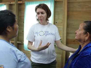 Woman in a white shirt talking with two women