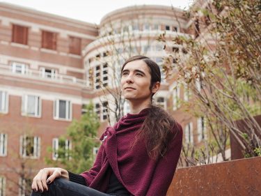 A student sits outside a brick building