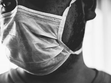 A black and white photo of a man wearing a face covering