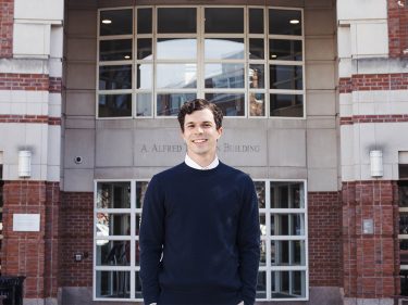 Jeremy Ney in a sweater outside a building