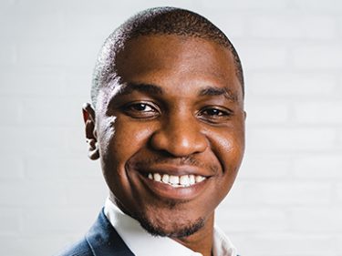 A man in front of a white brick wall