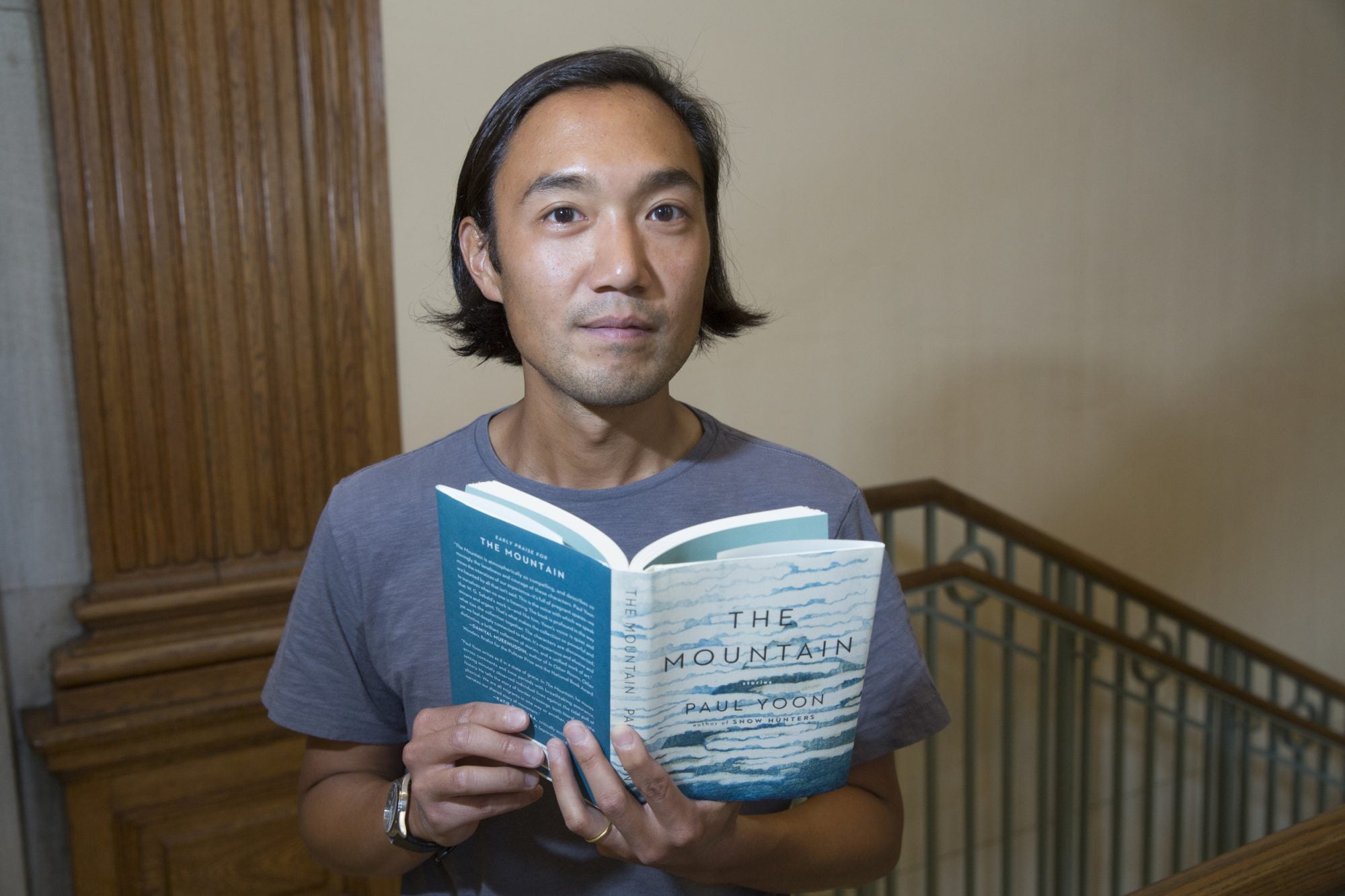A man stands holding a book entitled "The Mountain"