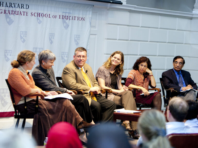 six people sitting on stage talking