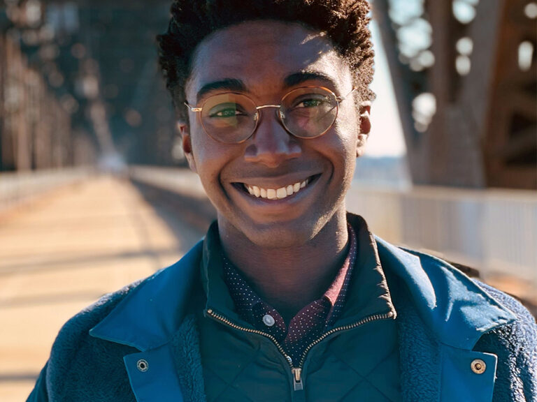 A student stands outside on a bridge