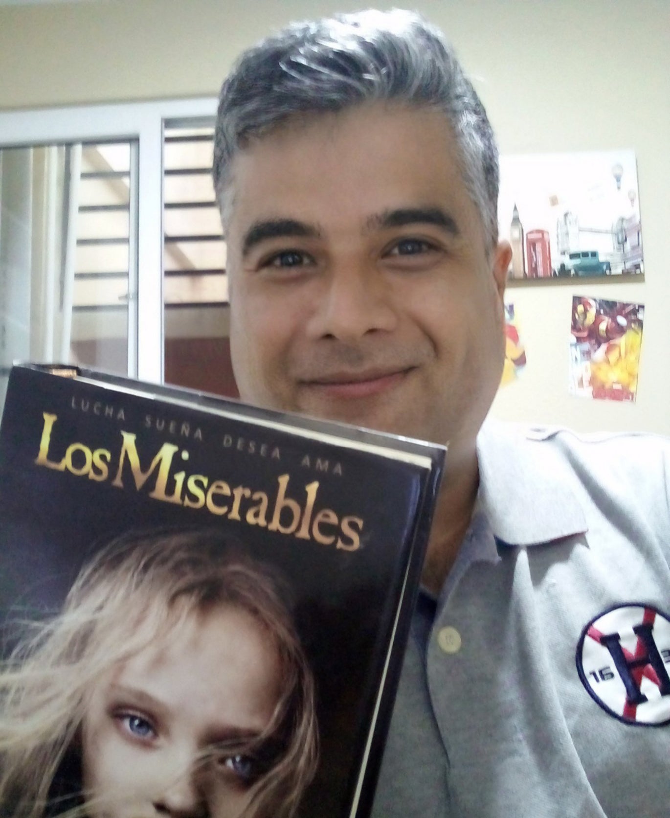 A man stands holding a book entitled "Los Miserables"