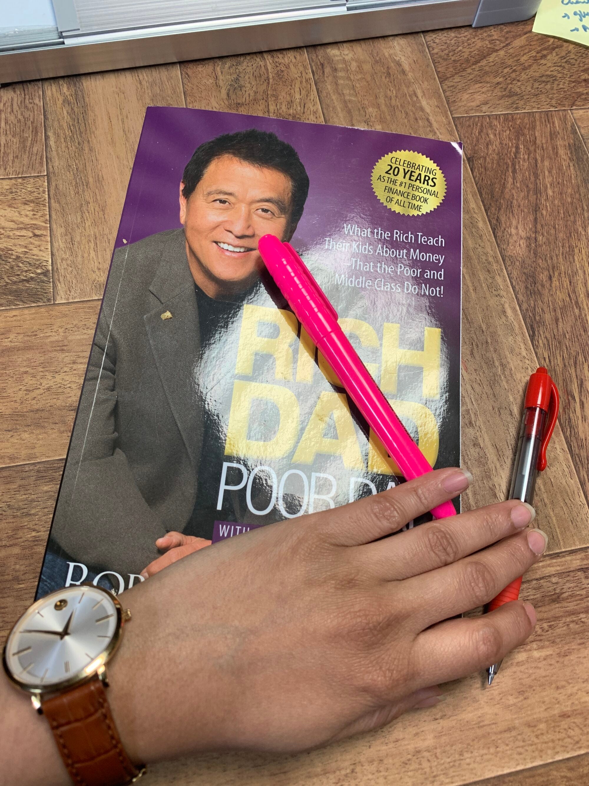 A hand on the book "Rich dad, poor dad"