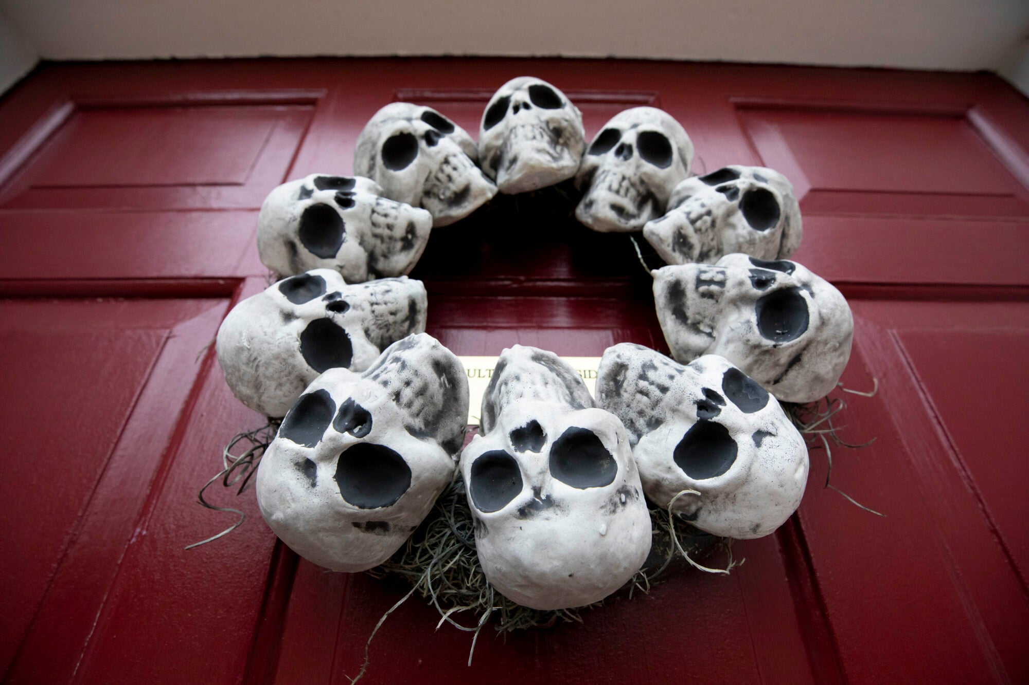 Skulls in a circle like a wreath hang on a red door