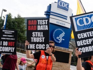 People hold signs at a protest against masks, vaccines, and vaccine passports