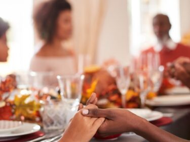 A family holds hands while sitting around the Thanksgiving table