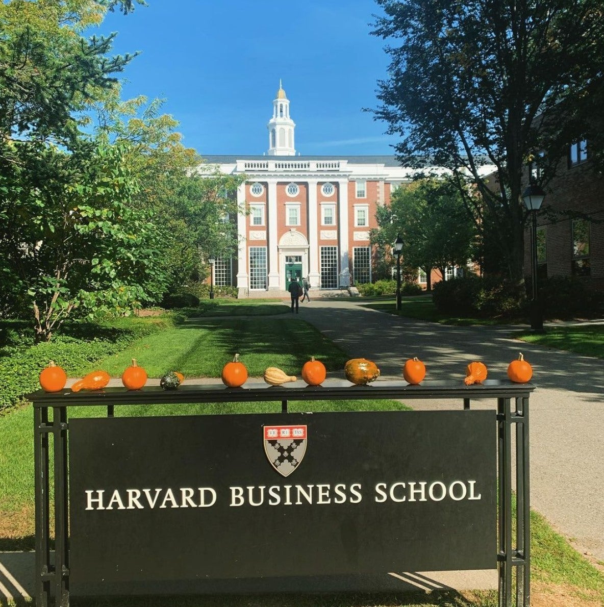 Pumpkins and gourds sit atop the HBS sign, with a brick building in the background