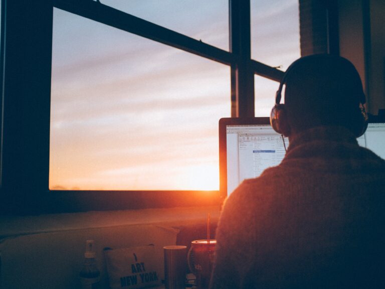 A person at a computer facing a sunrise
