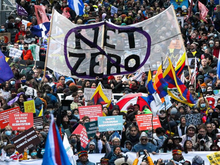 A crowd of people holding a sign that says "Net Zero"