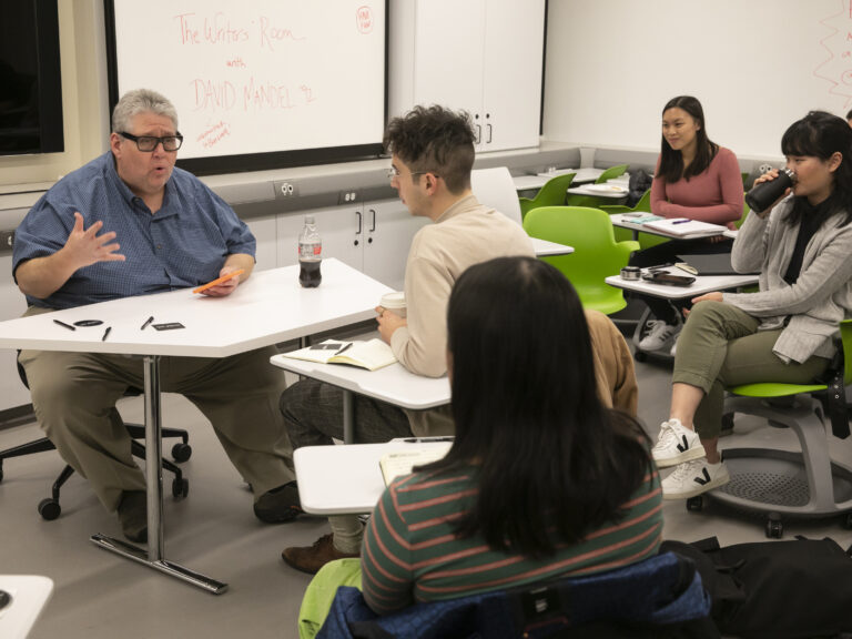 Students talking to a professor in a classroom