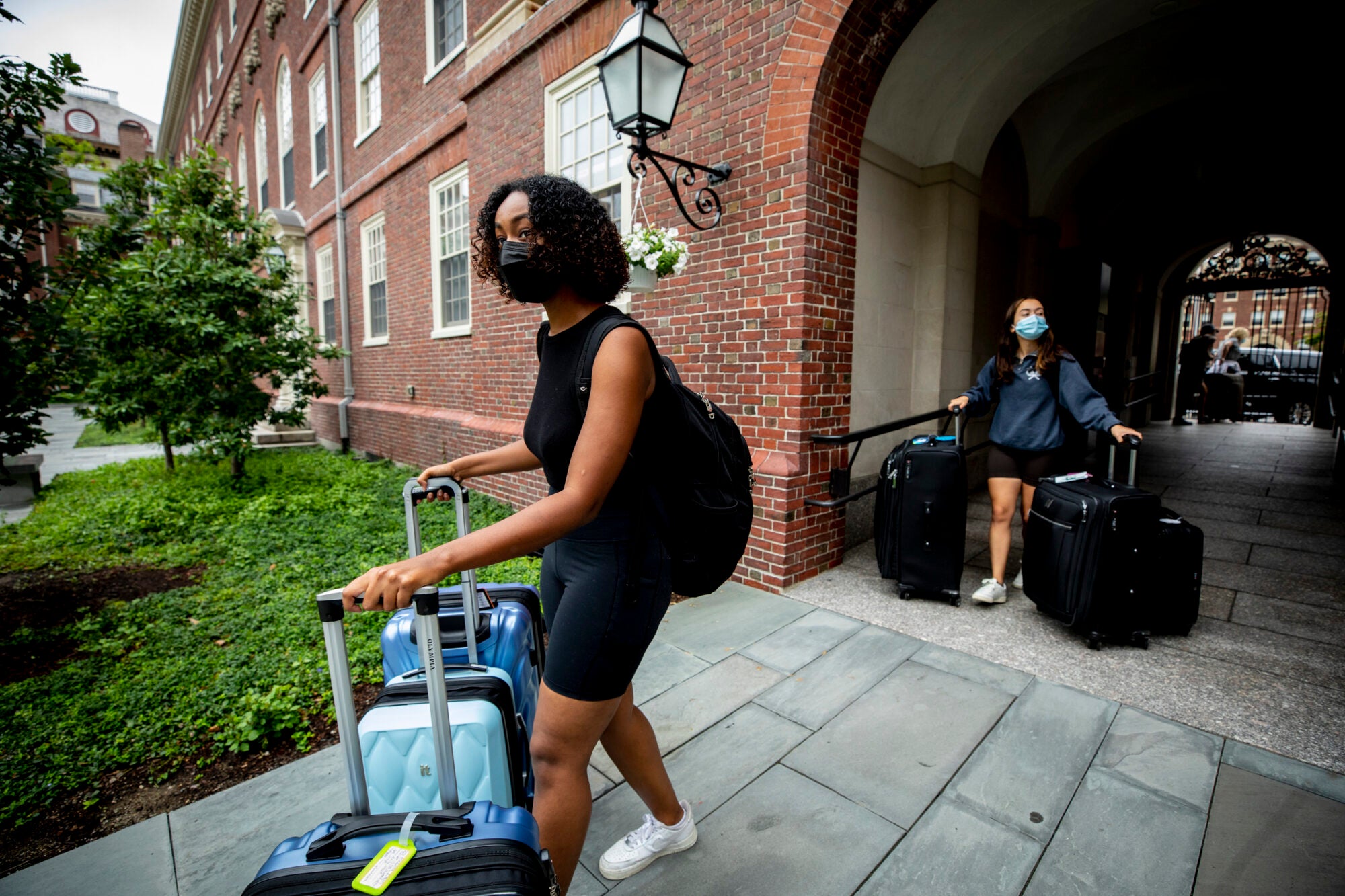 Students wheel luggage through the entry way of one of Harvard's dorms.