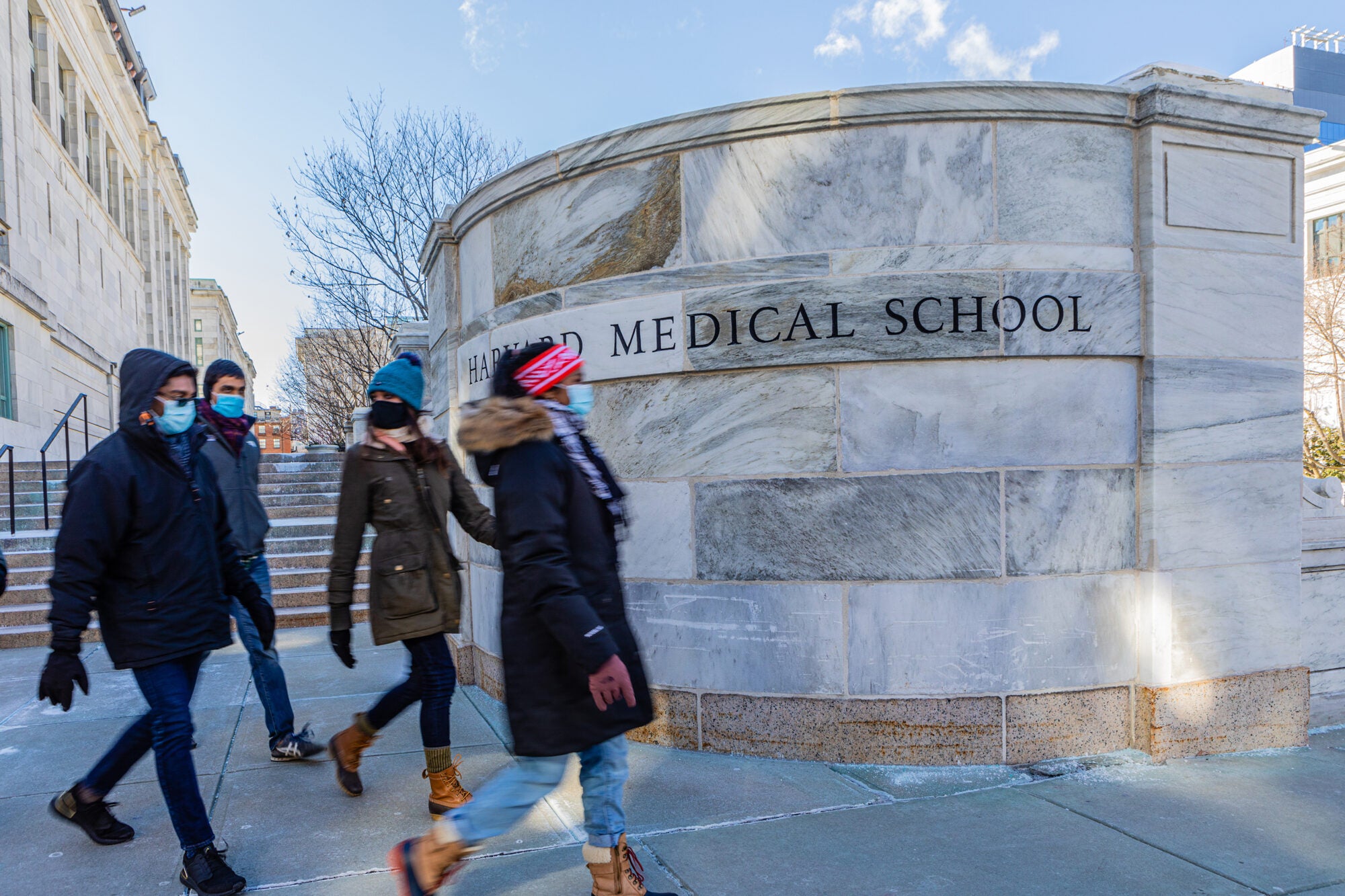 Students bundled in winter gear walk through Harvard Medical School's campus.
